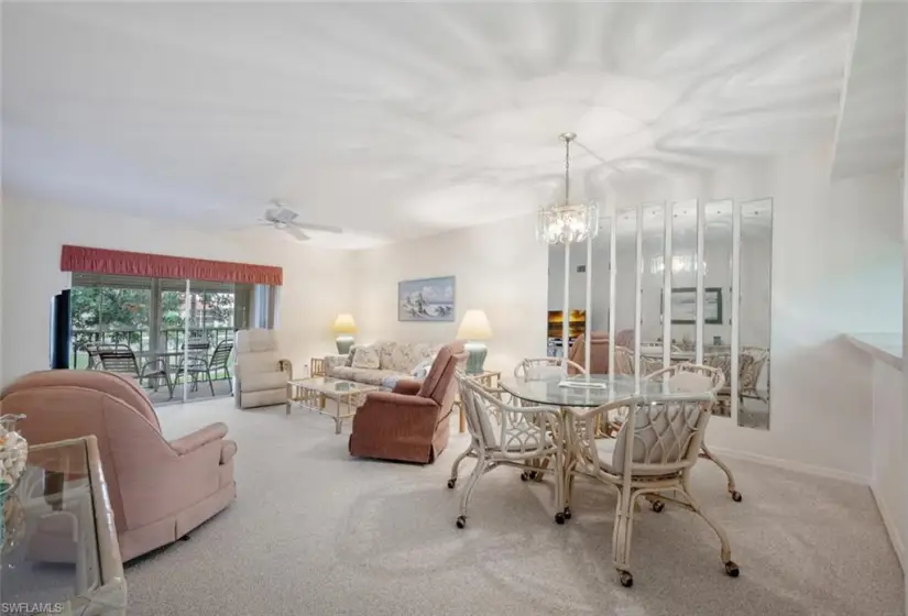 Carpeted dining area featuring ceiling fan with notable chandelier