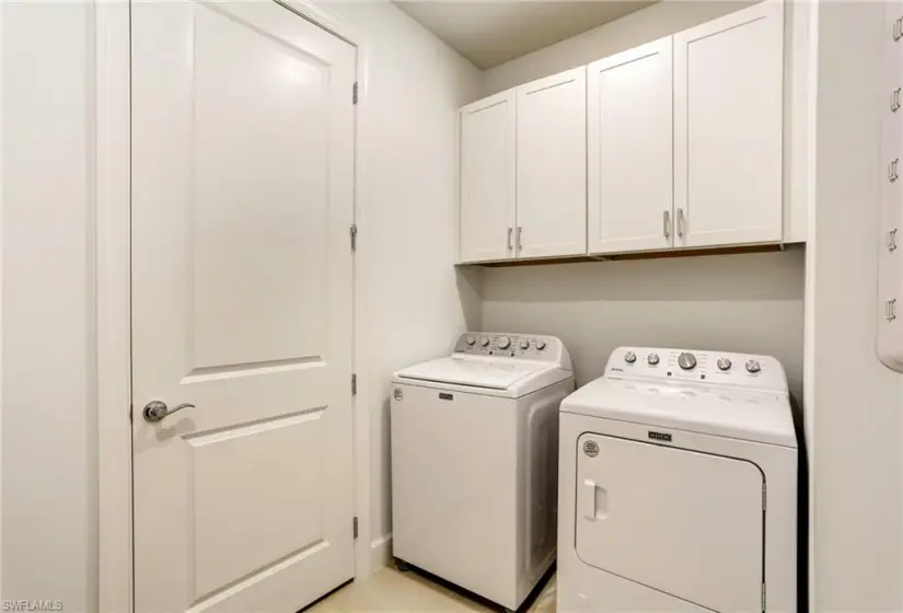 Washroom with washing machine and clothes dryer and cabinets