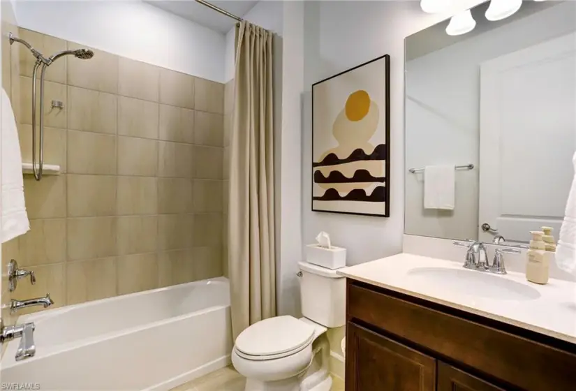 Full bathroom with shower / bathtub combination with curtain, vanity, and toilet