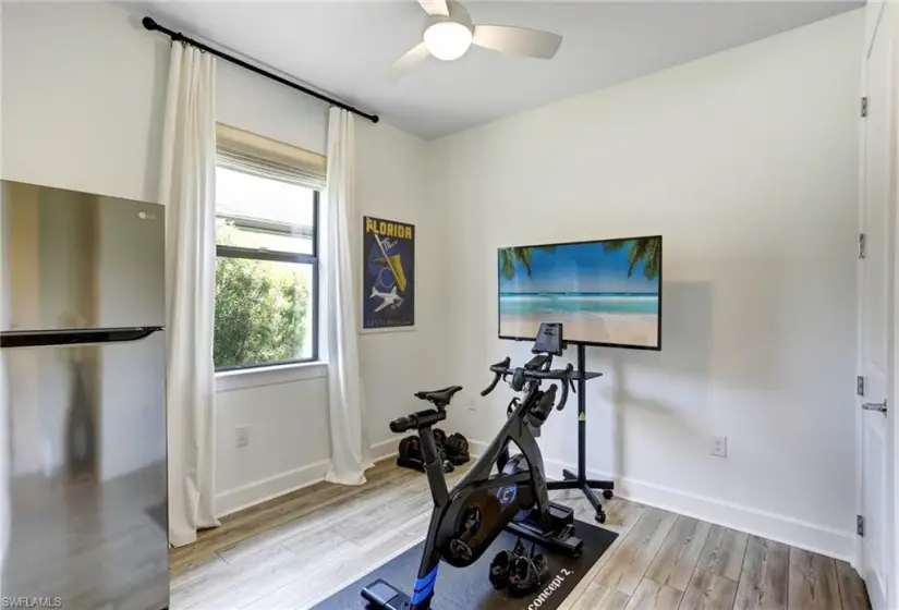 Exercise room with ceiling fan and light hardwood / wood-style floors