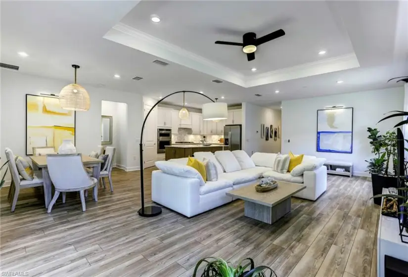 Living room featuring ceiling fan, light hardwood / wood-style floors, and a tray ceiling