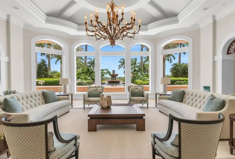 Living room featuring a tray ceiling, carpet floors, and a chandelier