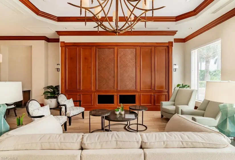 Living room with a tray ceiling, a chandelier, ornamental molding, and light hardwood / wood-style floors